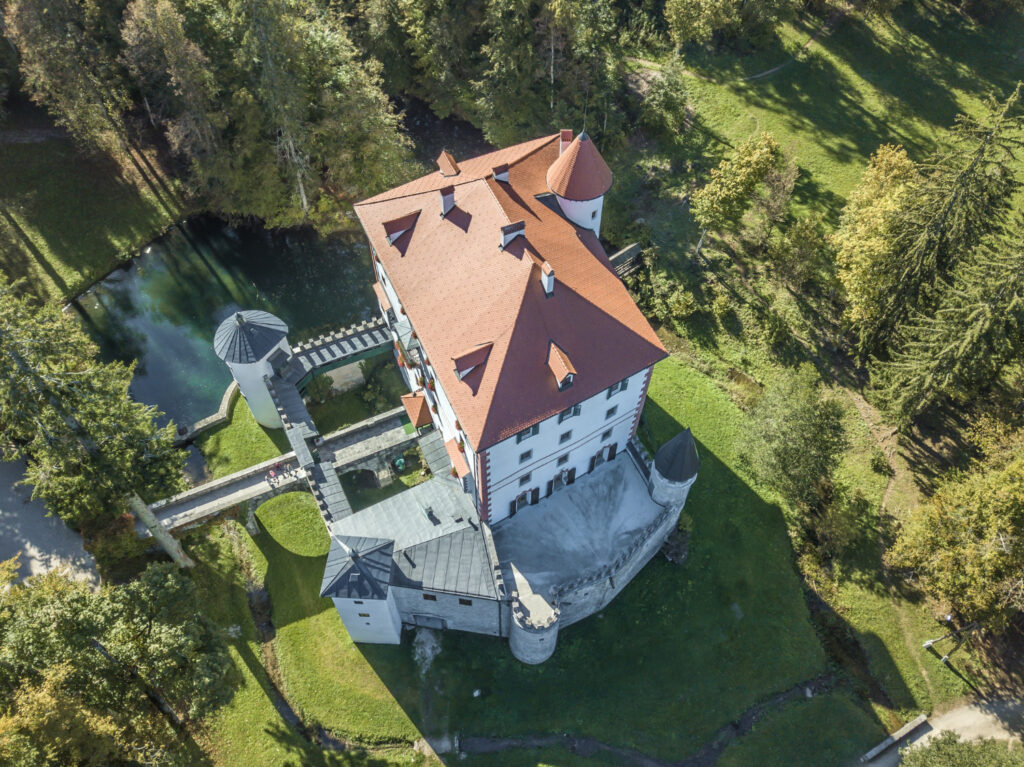 A large castle with a red roof and a bridge.