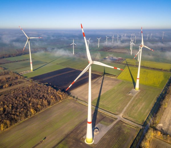 Aerial view of wind energy turbines on windfarm above mist layer on german countryside in the morning sun. Germany
